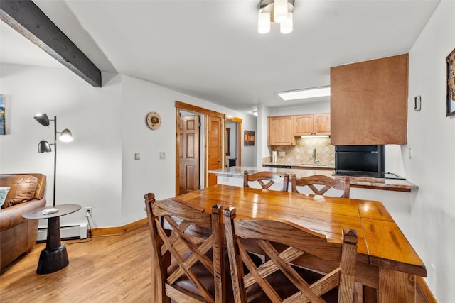 dining room with beam ceiling, light hardwood / wood-style floors, baseboard heating, and sink