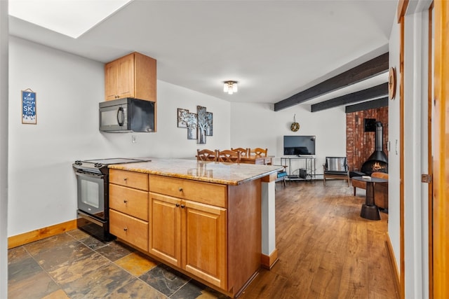 kitchen with beamed ceiling, kitchen peninsula, a wood stove, and black appliances