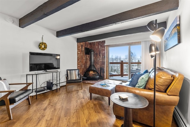 living room featuring beamed ceiling, a wood stove, hardwood / wood-style floors, and a baseboard heating unit