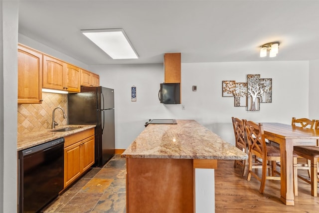 kitchen with tasteful backsplash, light stone counters, sink, and black appliances