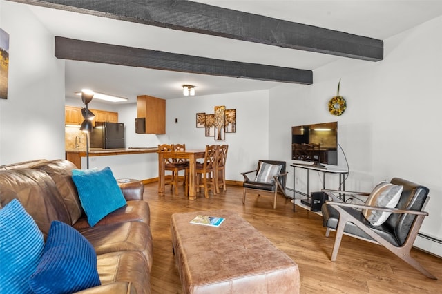 living room featuring beam ceiling, sink, a baseboard radiator, and light hardwood / wood-style flooring