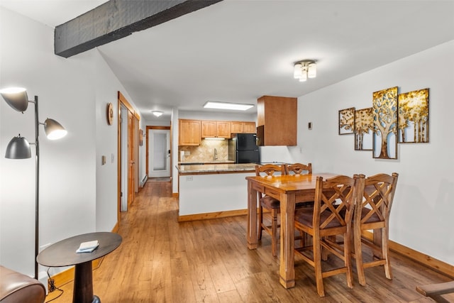 dining room with beam ceiling and light hardwood / wood-style flooring