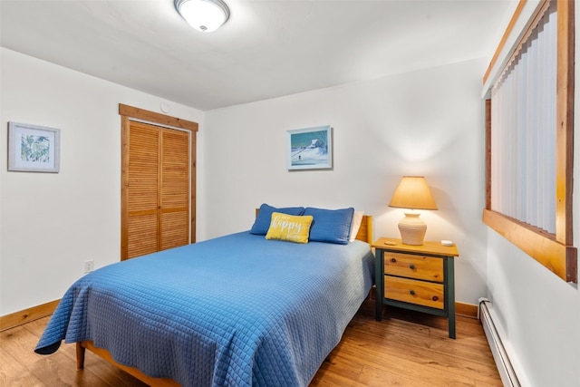 bedroom with hardwood / wood-style flooring, a baseboard heating unit, and a closet