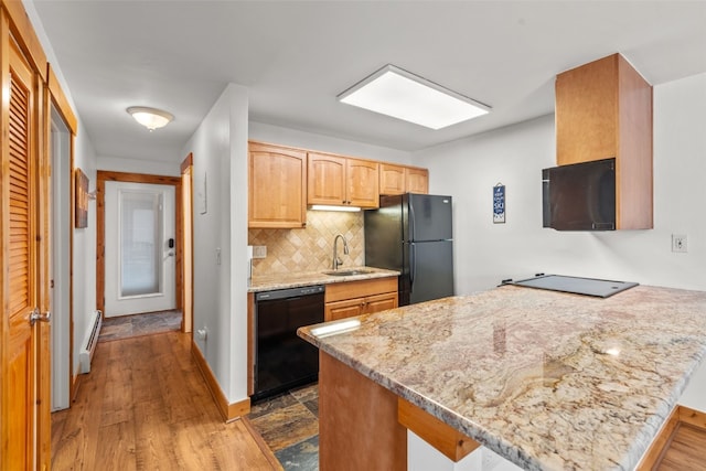 kitchen with kitchen peninsula, light stone countertops, tasteful backsplash, sink, and black appliances