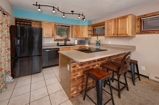 kitchen with light tile patterned floors, a breakfast bar, a sink, black appliances, and light countertops