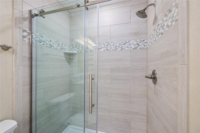 bathroom featuring a shower with door and toilet