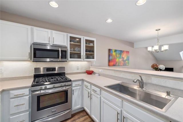 kitchen with sink, hanging light fixtures, white cabinets, and appliances with stainless steel finishes