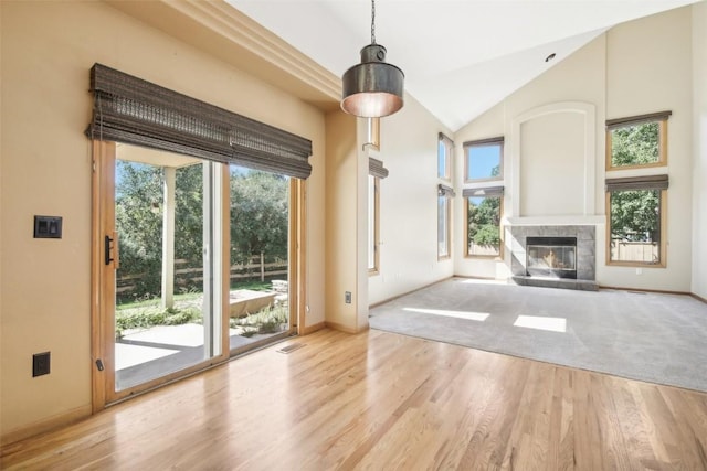 unfurnished living room featuring a tile fireplace, lofted ceiling, and light wood-type flooring