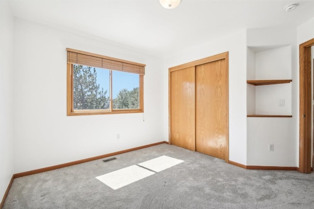 unfurnished bedroom featuring light carpet and a closet