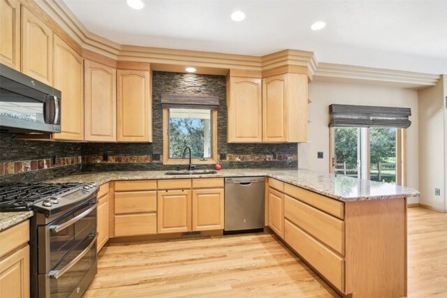 kitchen with sink, light stone countertops, light brown cabinetry, kitchen peninsula, and stainless steel appliances