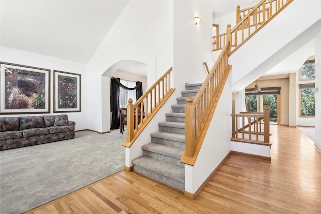 staircase featuring wood-type flooring and a high ceiling