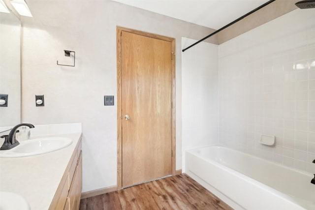 bathroom with hardwood / wood-style flooring, vanity, and tiled shower / bath