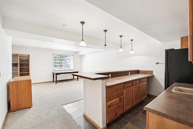 kitchen featuring pendant lighting, black refrigerator, kitchen peninsula, and dark colored carpet