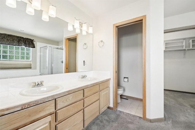 bathroom with tile patterned flooring, vanity, an enclosed shower, and toilet