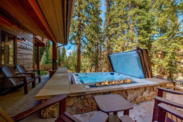 view of patio / terrace with a covered hot tub and a fire pit