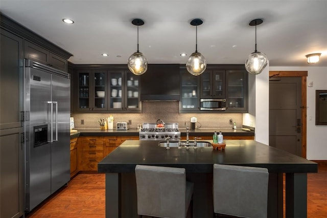 kitchen featuring premium range hood, hanging light fixtures, dark hardwood / wood-style floors, and appliances with stainless steel finishes