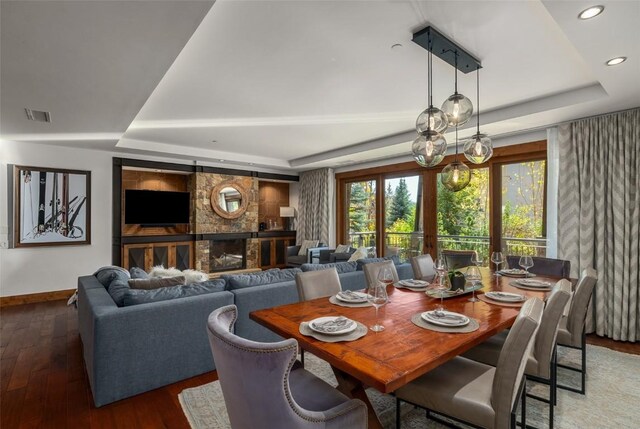 dining area with a tray ceiling, a fireplace, french doors, and dark hardwood / wood-style floors