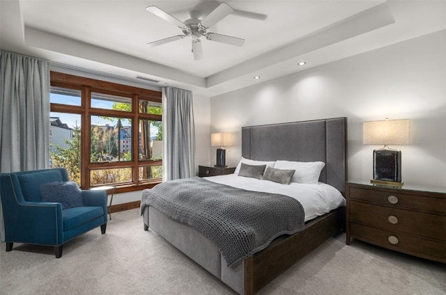 carpeted bedroom featuring ceiling fan and a tray ceiling