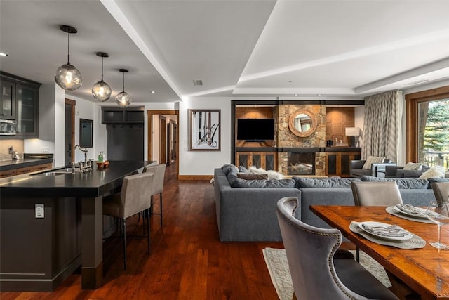 living room with a fireplace, dark hardwood / wood-style floors, a raised ceiling, and sink