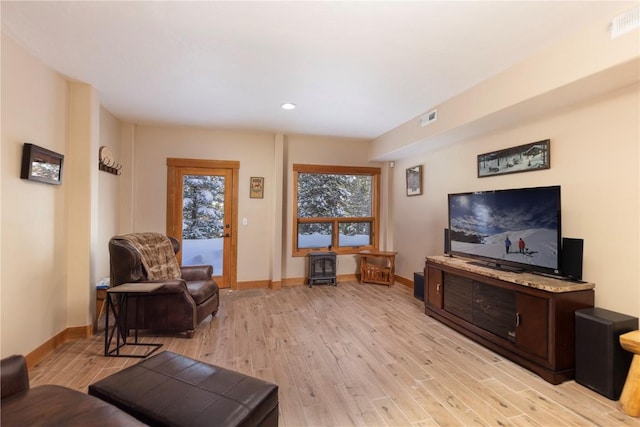 living room with a wood stove and light hardwood / wood-style flooring