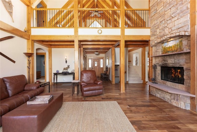 living room featuring a stone fireplace, hardwood / wood-style floors, and a towering ceiling