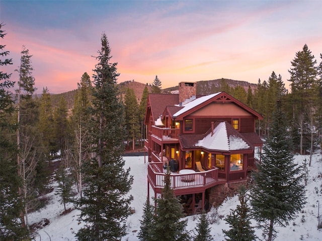 snow covered property with a deck with mountain view