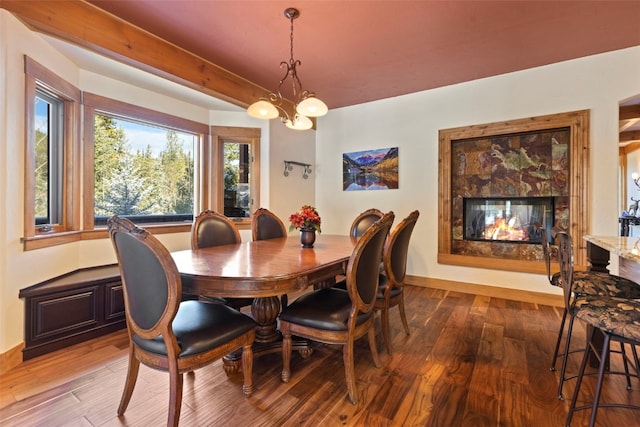 dining area featuring a fireplace, wood-type flooring, and a notable chandelier