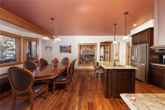 dining space featuring a chandelier, dark hardwood / wood-style floors, a tile fireplace, and sink