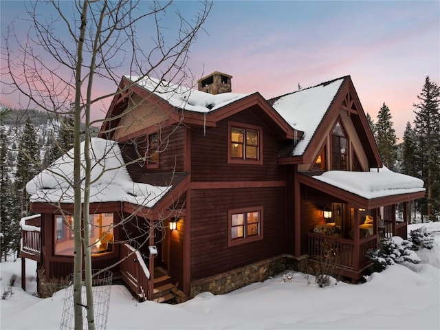 snow covered back of property with covered porch