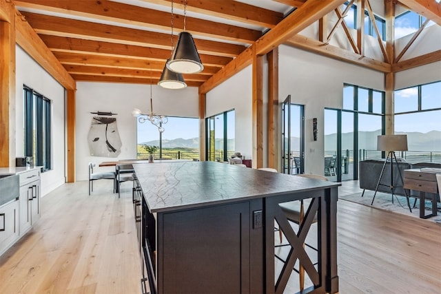 kitchen with a mountain view, beam ceiling, decorative light fixtures, and light hardwood / wood-style floors