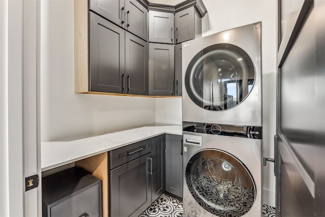 laundry area with cabinets and stacked washer and clothes dryer