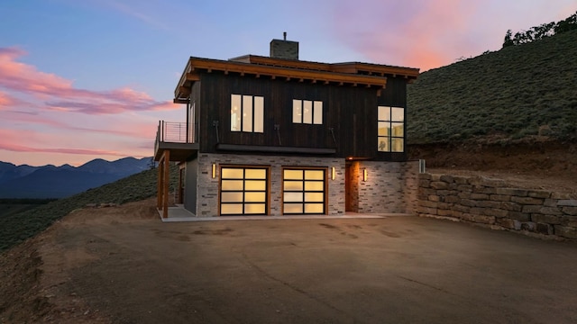 back house at dusk featuring a mountain view, a garage, a balcony, and central AC