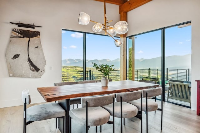 dining room featuring a mountain view, beamed ceiling, and light hardwood / wood-style floors