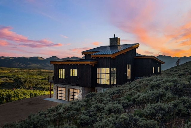 back house at dusk featuring a mountain view and a garage