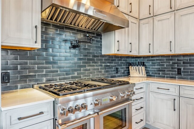 kitchen featuring backsplash, stainless steel range, and wall chimney range hood