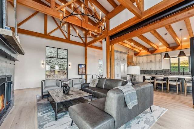 living room featuring beam ceiling, light hardwood / wood-style flooring, and high vaulted ceiling