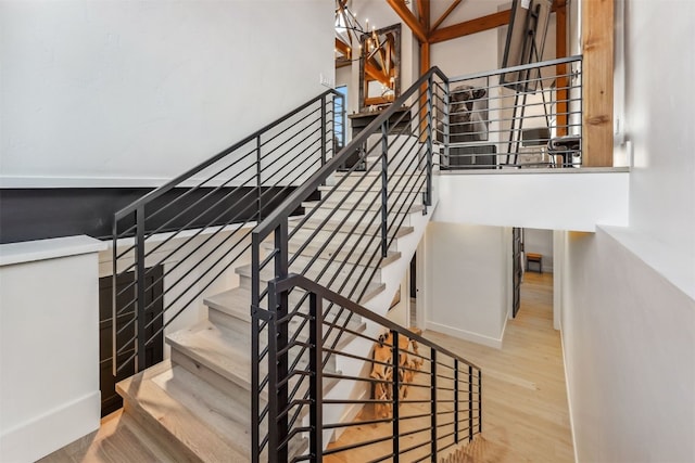 staircase with hardwood / wood-style floors and a notable chandelier