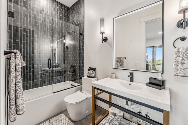 full bathroom featuring sink, toilet, and combined bath / shower with glass door