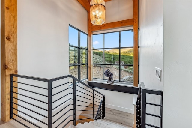 stairs with wood-type flooring and a notable chandelier