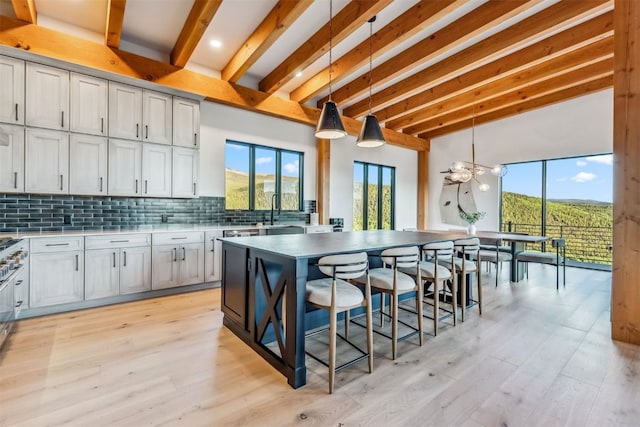 kitchen featuring tasteful backsplash, a kitchen breakfast bar, beamed ceiling, decorative light fixtures, and a kitchen island