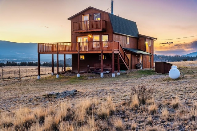 back house at dusk featuring a balcony and a deck with mountain view