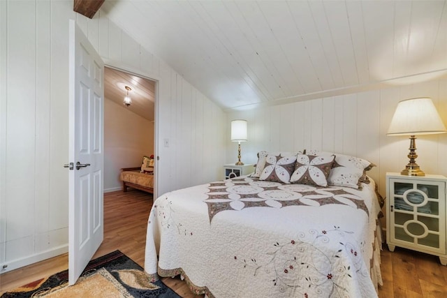 bedroom with hardwood / wood-style flooring, vaulted ceiling, wooden ceiling, and wood walls