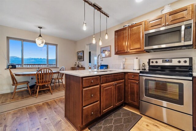 kitchen with a mountain view, appliances with stainless steel finishes, kitchen peninsula, and sink