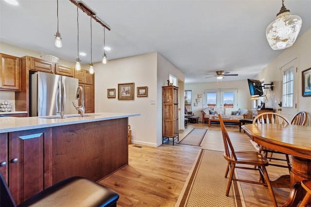 kitchen with stainless steel fridge, light hardwood / wood-style floors, ceiling fan, and pendant lighting