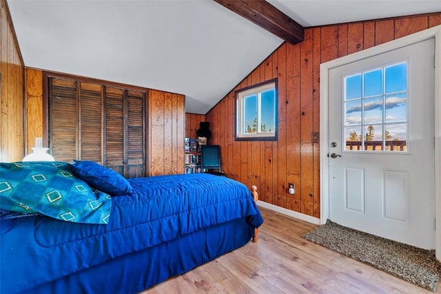 bedroom featuring lofted ceiling with beams, light hardwood / wood-style flooring, and wood walls