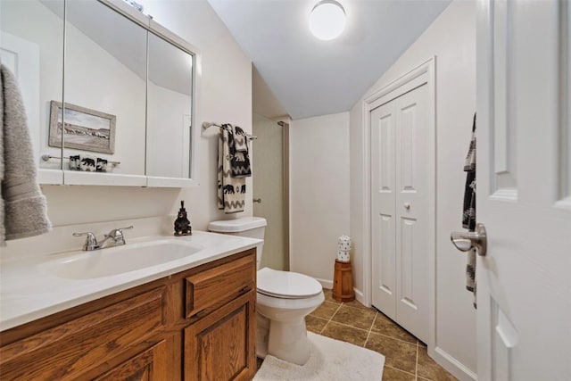 bathroom featuring tile patterned flooring, vanity, toilet, and vaulted ceiling