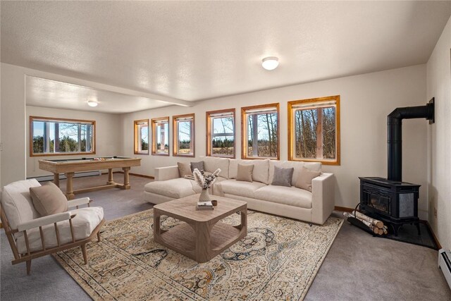 carpeted living room featuring a wood stove, a baseboard heating unit, and pool table