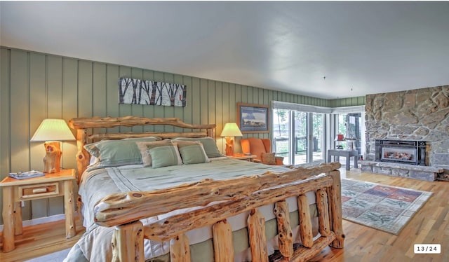 bedroom featuring access to exterior, wood finished floors, and a fireplace