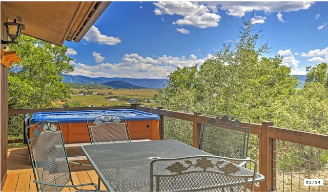 wooden deck featuring outdoor dining space, a mountain view, and a hot tub