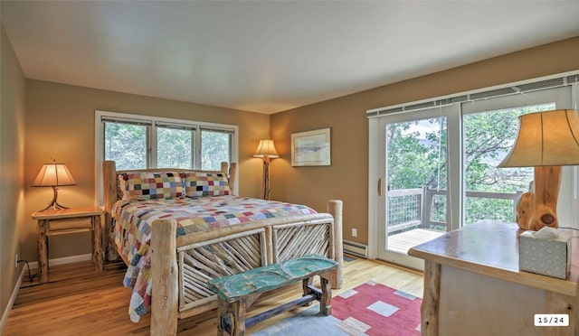 bedroom featuring access to exterior, light wood-style flooring, a baseboard heating unit, and baseboards